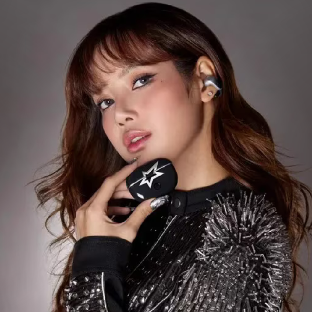 Woman wearing Bose Ultra Open Earbuds, holding a branded charging case, styled in a studded black outfit.