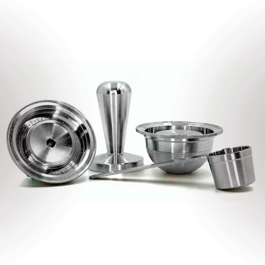 Stainless steel reusable coffee pod kit including tamper, scoop, and refillable capsule components.